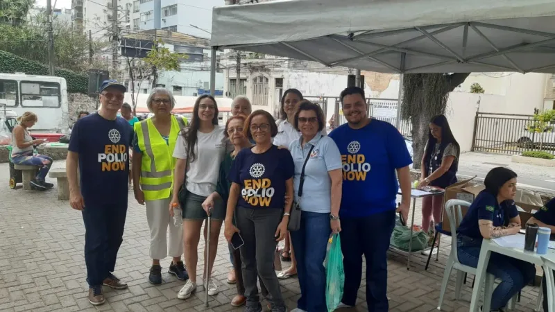 Rotarianos com camisetas End Polio Now na tenda da vacinação